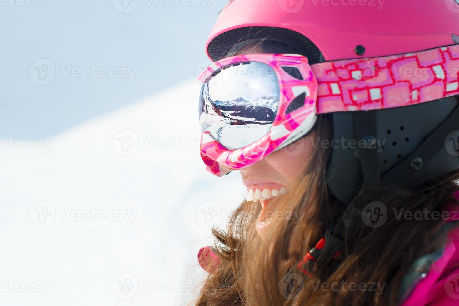 Female skier with skis smiling and wearing ski glasses photo