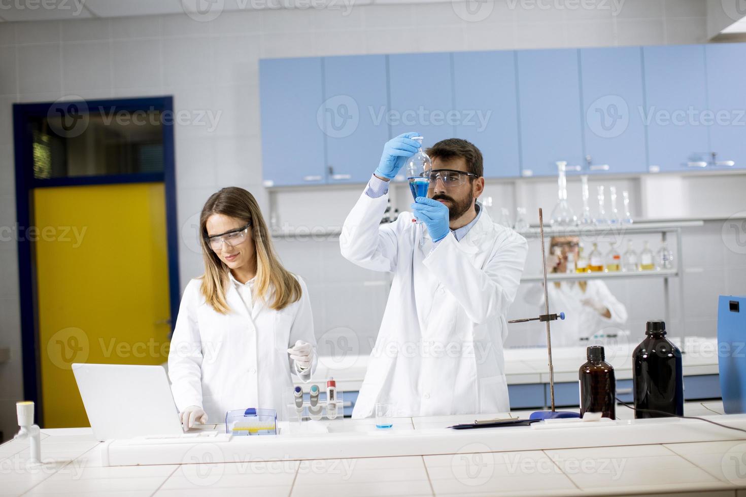 Researcher working with blue liquid at laboratory glass photo