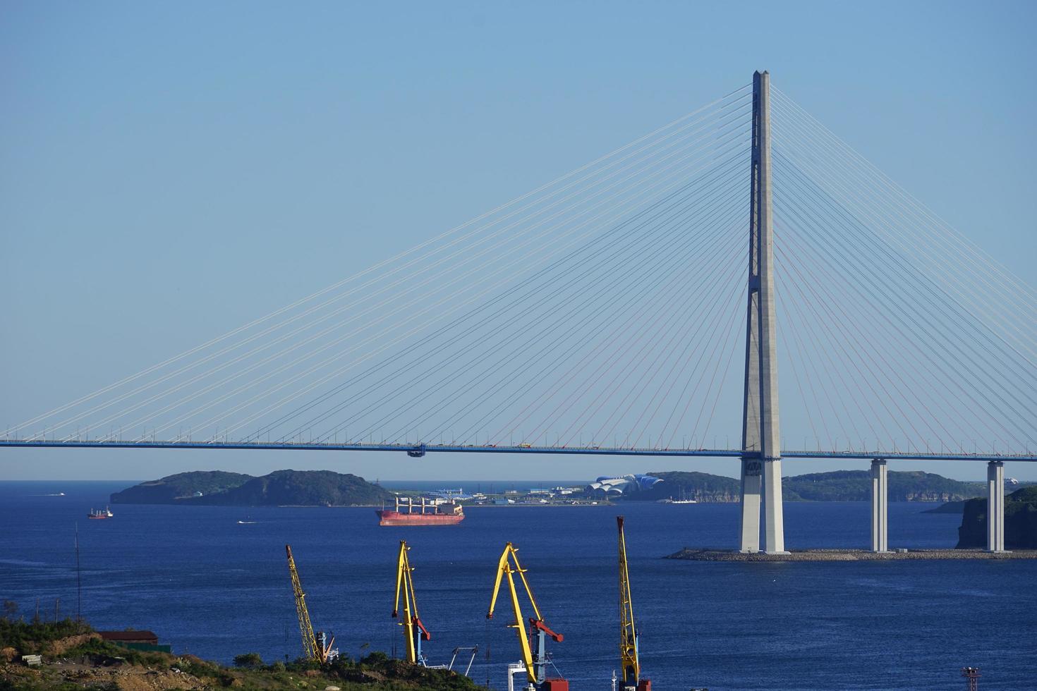 Paisaje marino del puente russky y una costa con grúas de construcción en Vladivostok, Rusia foto