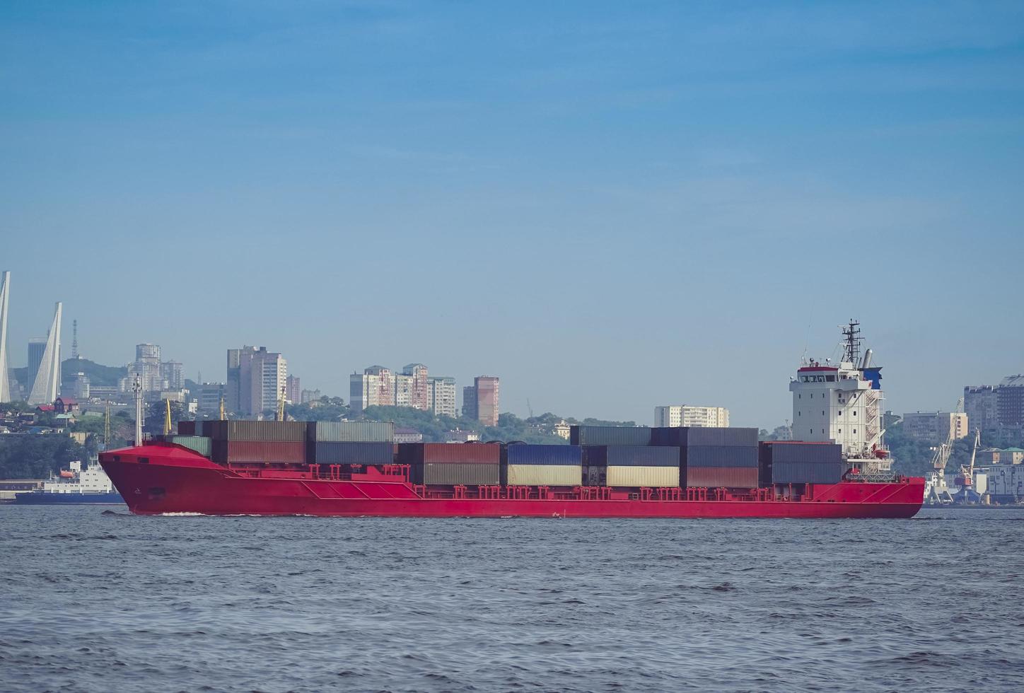 Seascape with a red container ship and city skyline in the background in Vladivostok, Russia photo