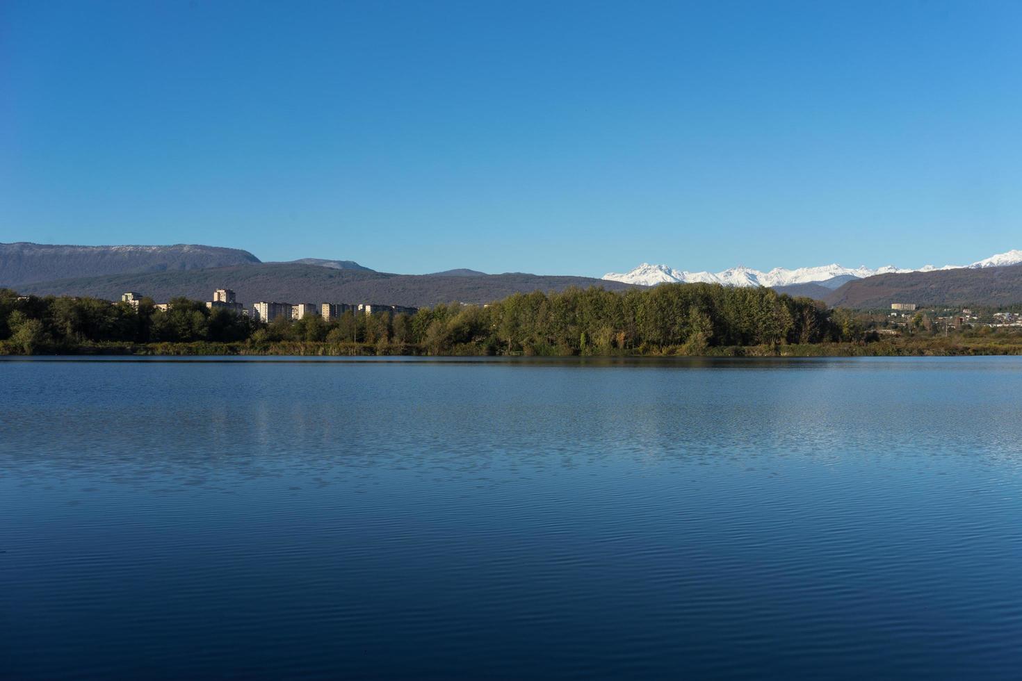 paisaje de un lago con casas y bosque con cielo azul claro foto