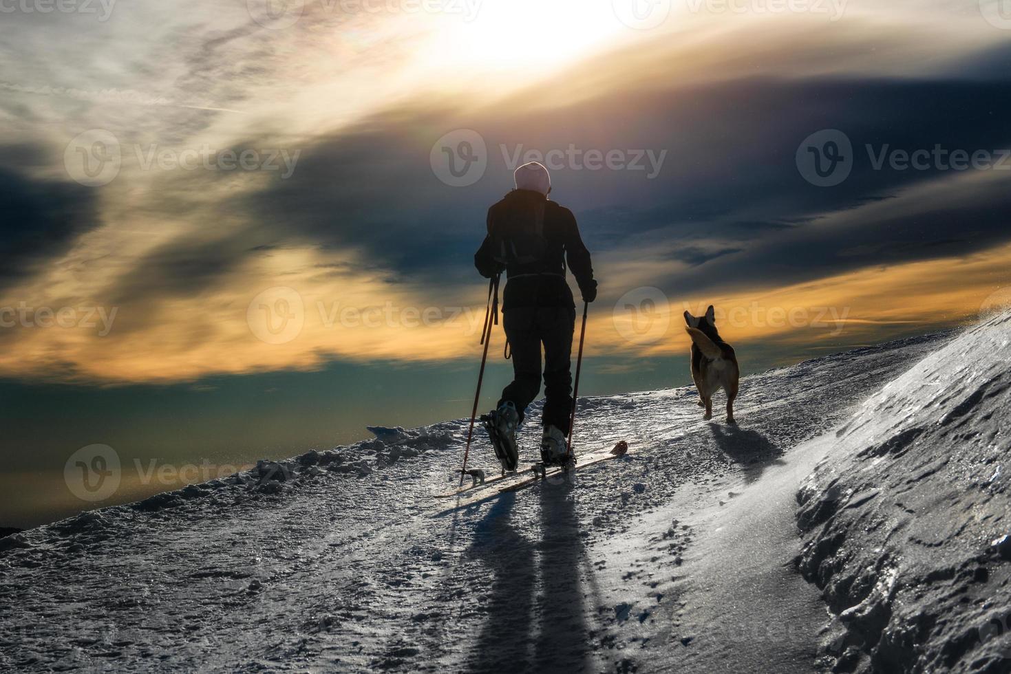 silueta de montañismo de esquí, niña con un perro foto