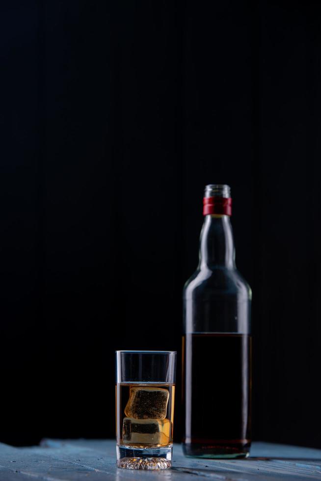 Still life with glass and bottle of alcohol on wooden table photo