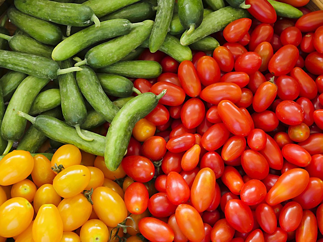 Red and orange tomatoes and green cucumber at the market photo