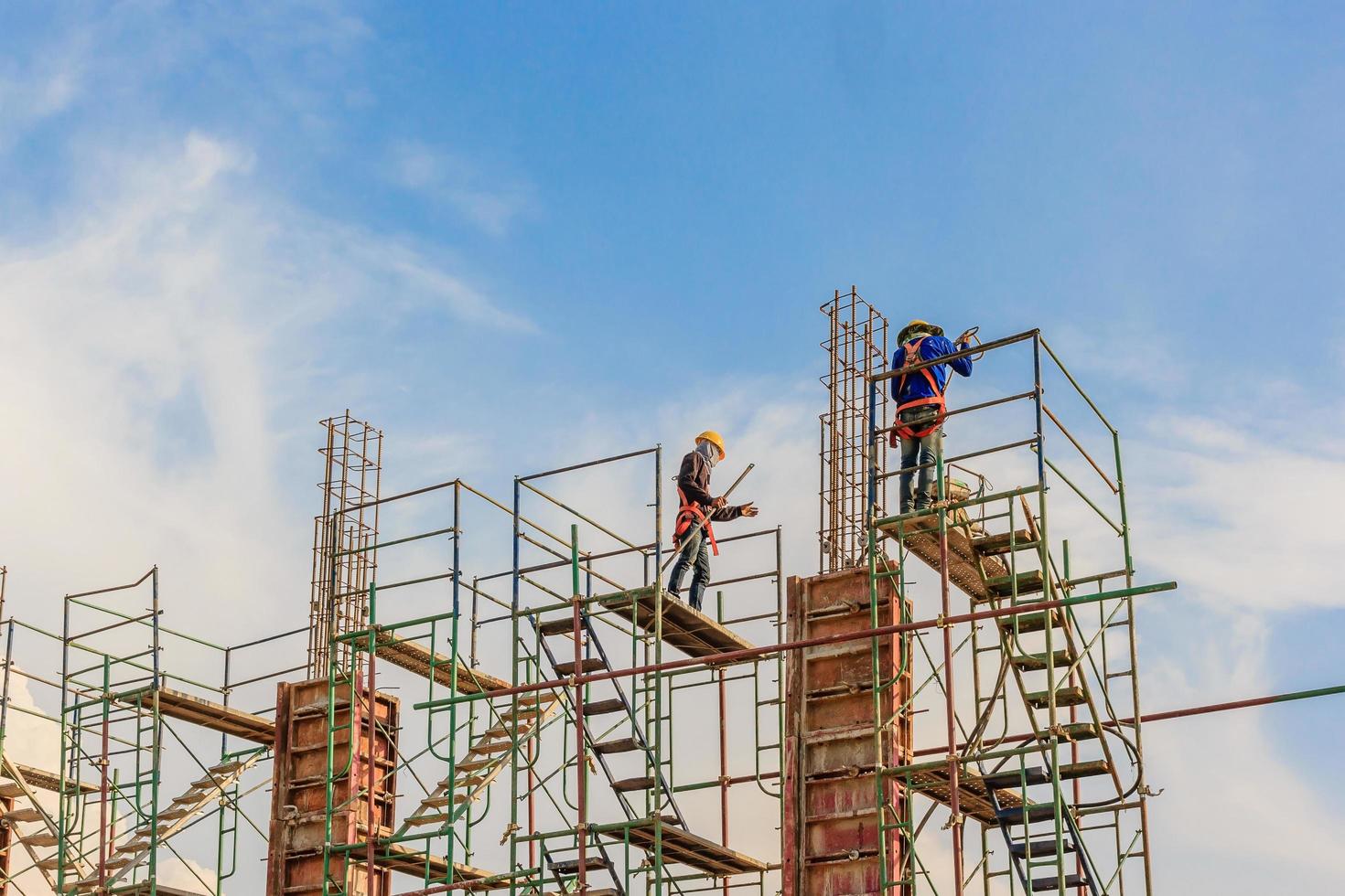 Construction workers working on scaffolding at a high level by safety standards set photo