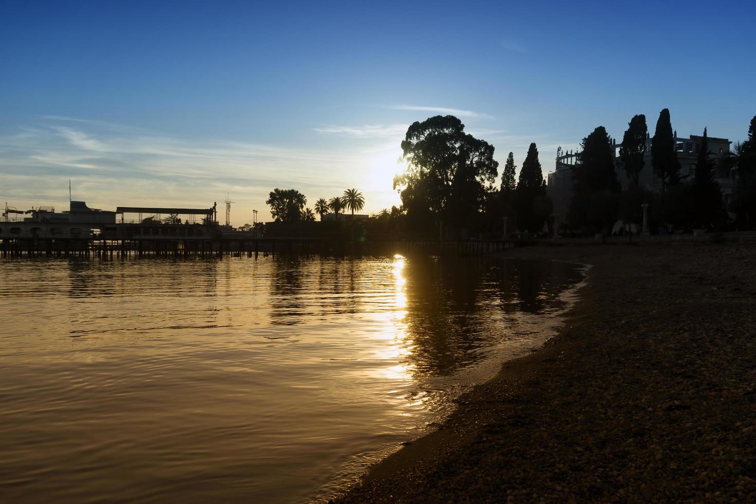 Silueta de un muelle y árboles con un nublado cielo azul atardecer en Sujumi, Abjasia, Georgia foto