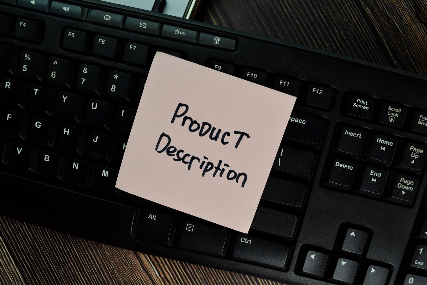 Product description written on sticky note isolated on keyboard and wooden table photo