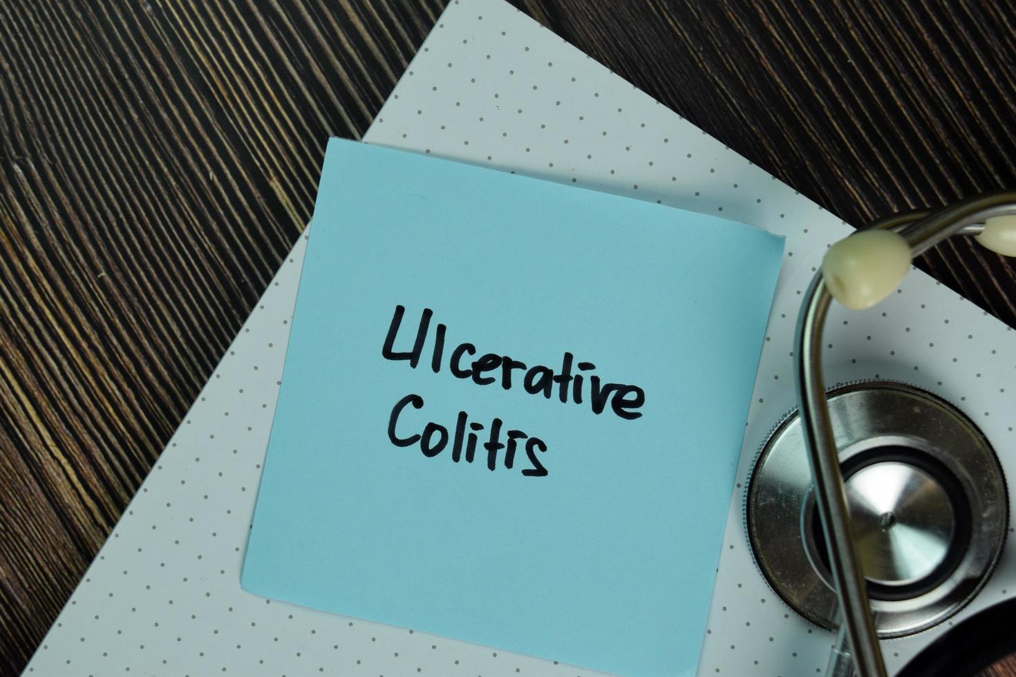 Ulcerative Colitis written on sticky note isolated on wooden table photo