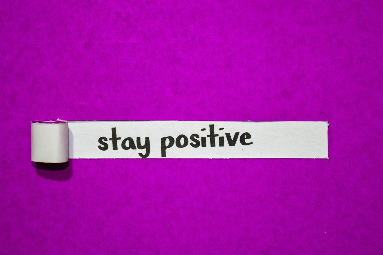 Manténgase positivo con el texto, la inspiración, la motivación y el concepto empresarial en papel rasgado púrpura foto
