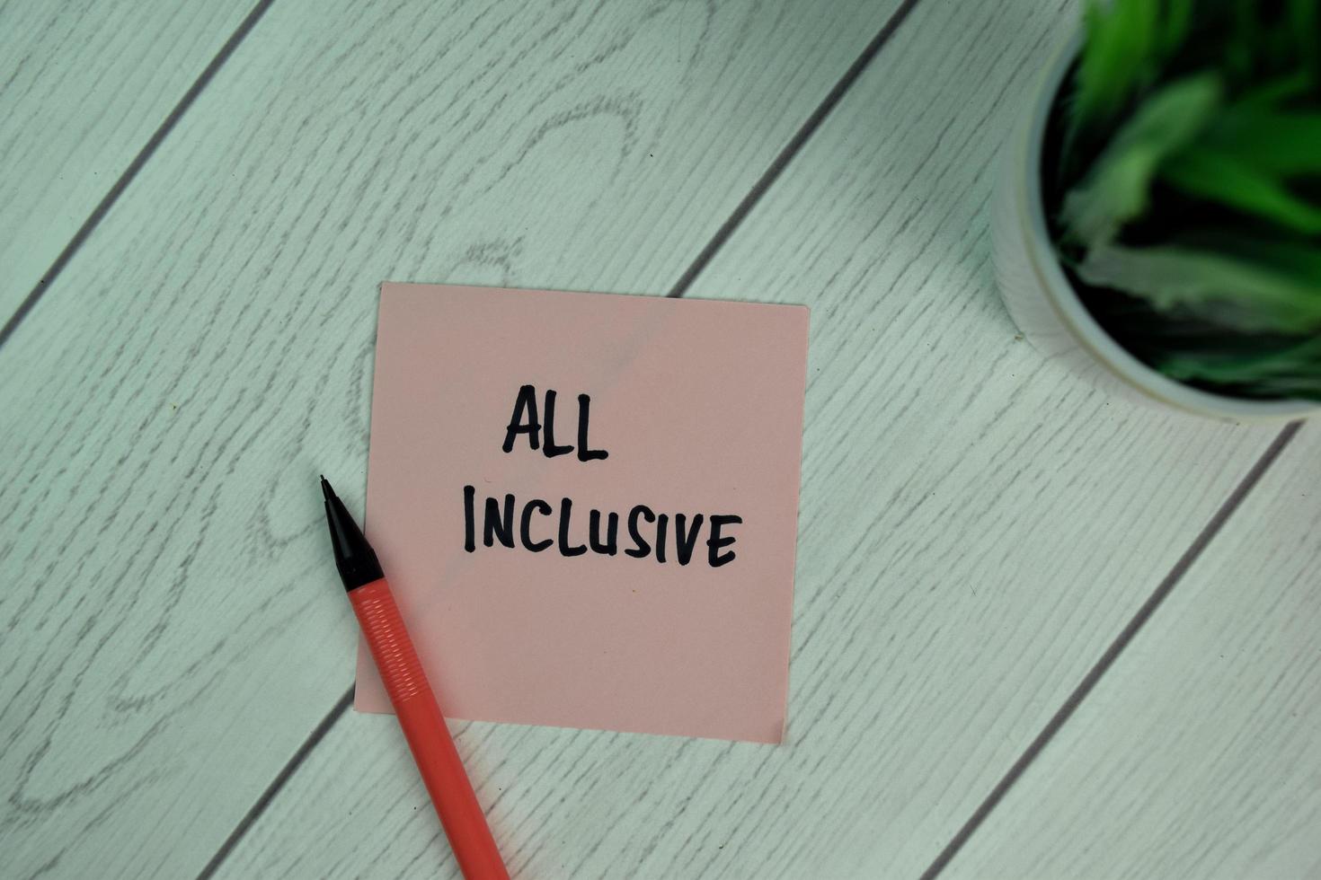 All Inclusive written on sticky note isolated on wooden table photo