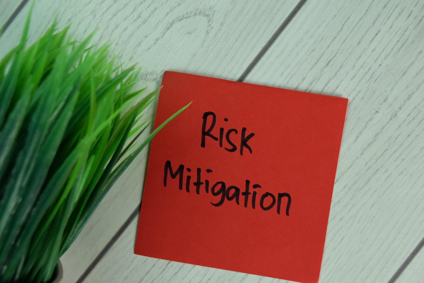 Risk Mitigation written on sticky note isolated on wooden table photo