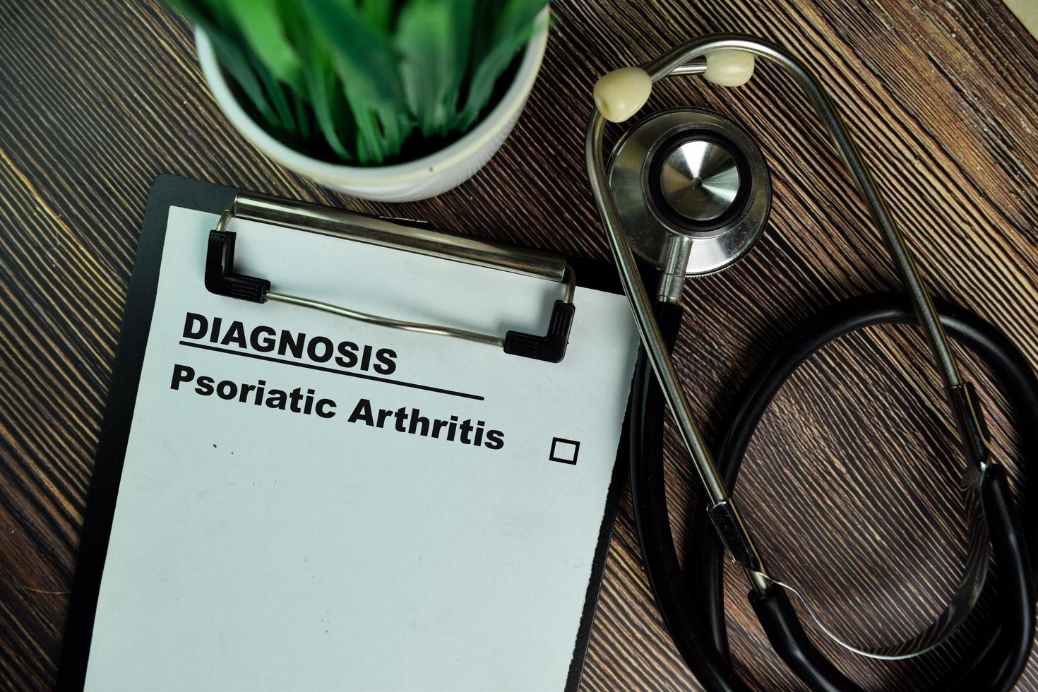 Diagnosis - Psoriatic Arthritis written on paperwork isolated on wooden table photo