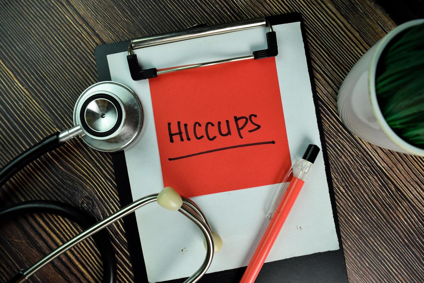 HICCUPS written on sticky note isolated on wooden table photo