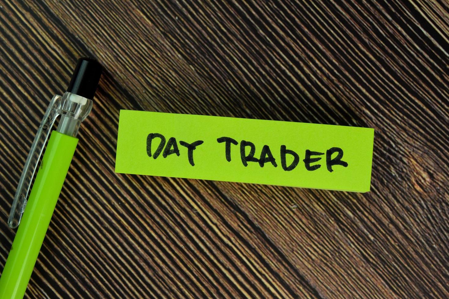 Day Trader written on sticky note isolated on wooden table photo