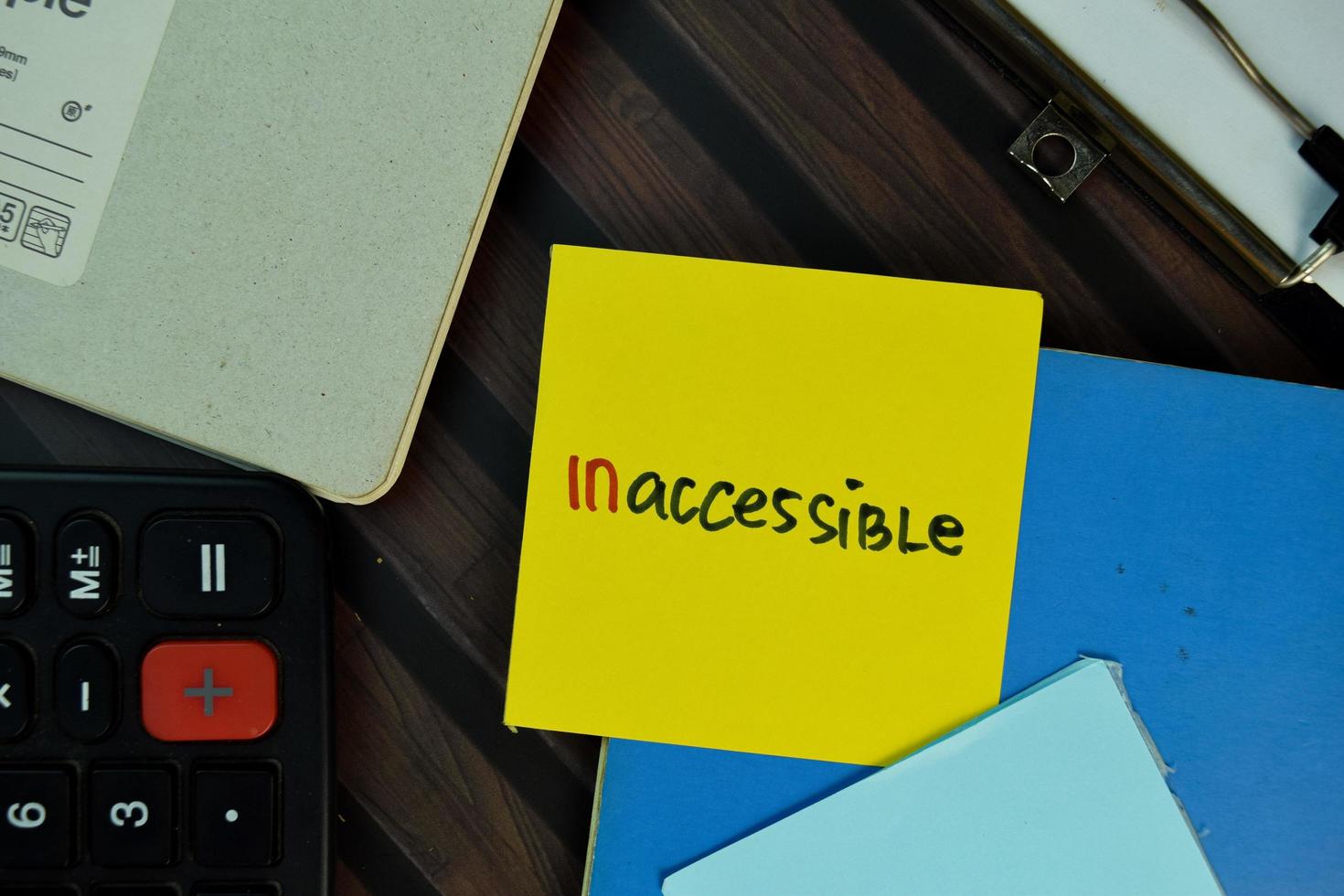 Inaccessible written on sticky note isolated on wooden table. photo