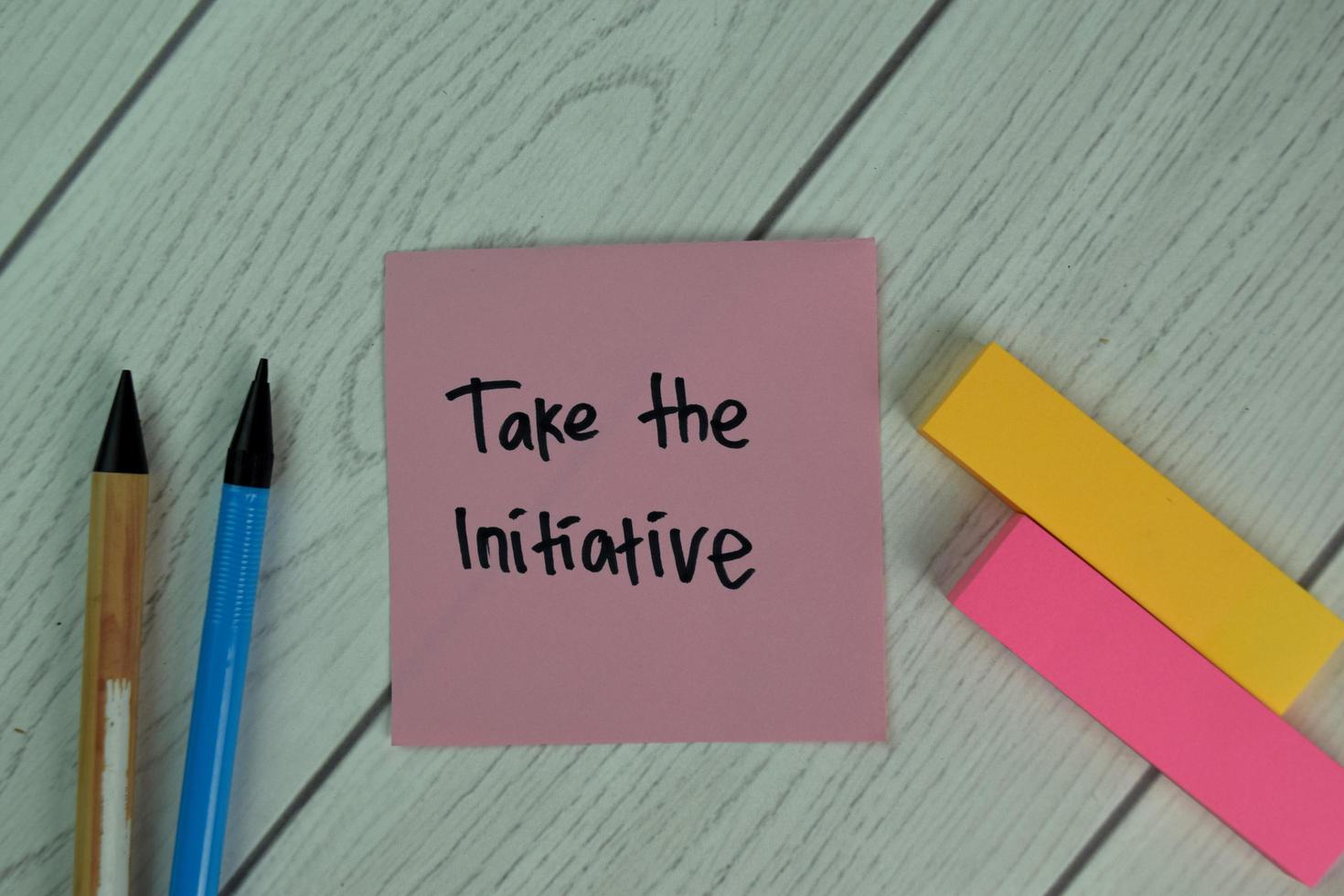 Take The Initiative written on sticky note isolated on wooden table photo