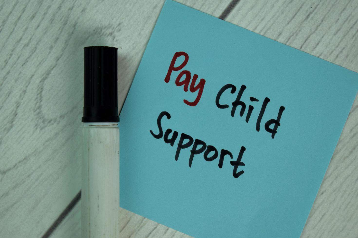 Pay Child Support written on sticky note isolated on wooden table photo