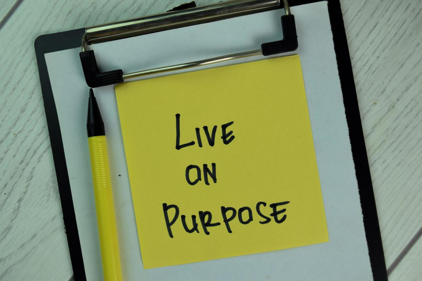 Live on Purpose written on sticky note isolated on wooden table photo