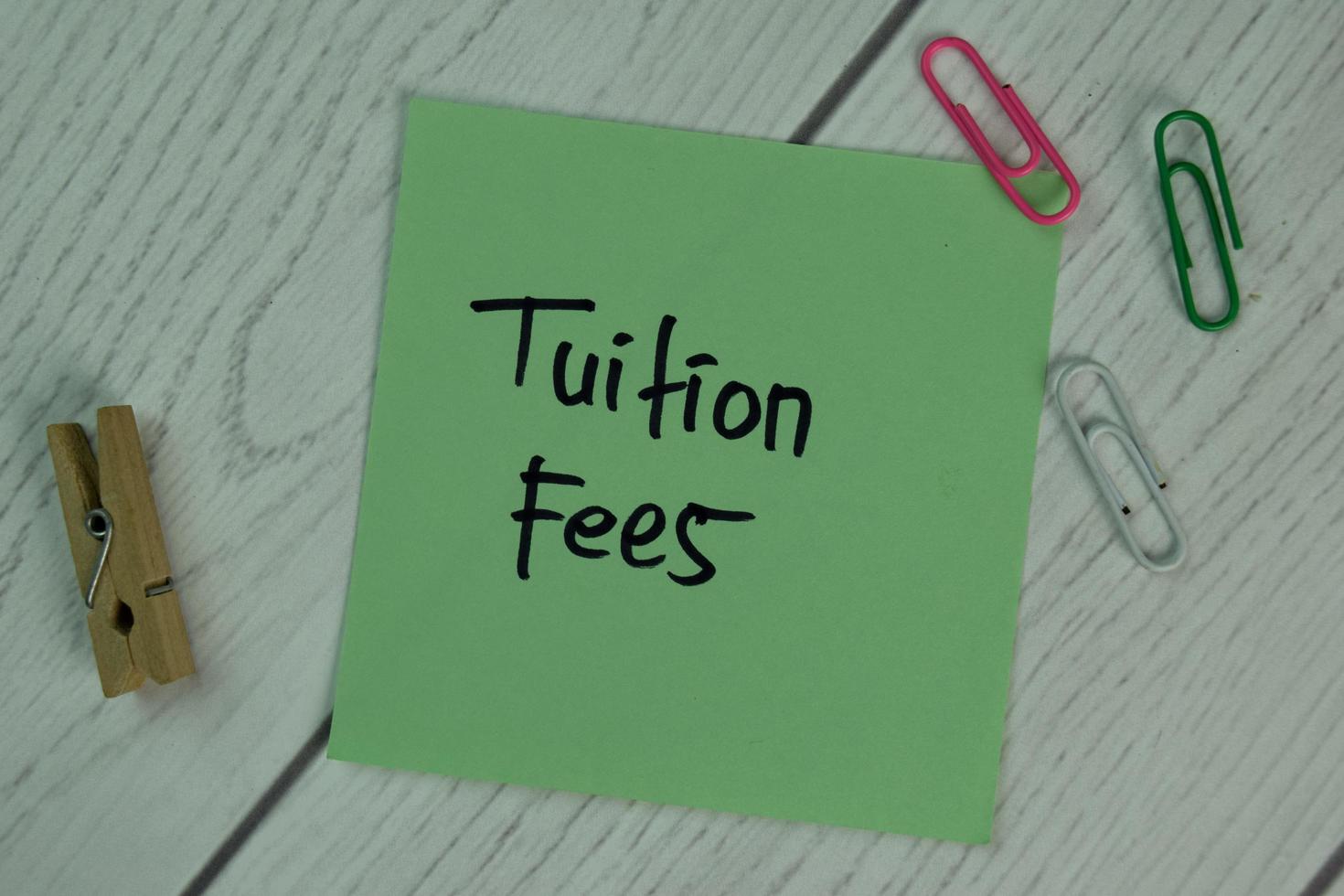 Tuition Fees written on sticky note isolated on wooden table photo