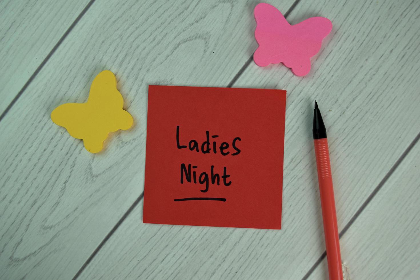 Ladies Night written on sticky note isolated on wooden table photo