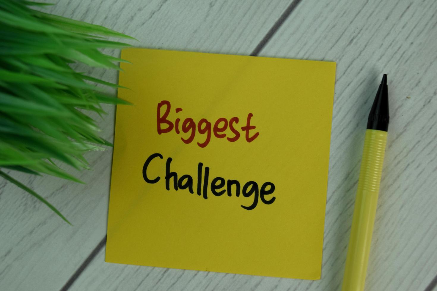 Biggest Challenge written on sticky note isolated on wooden table photo