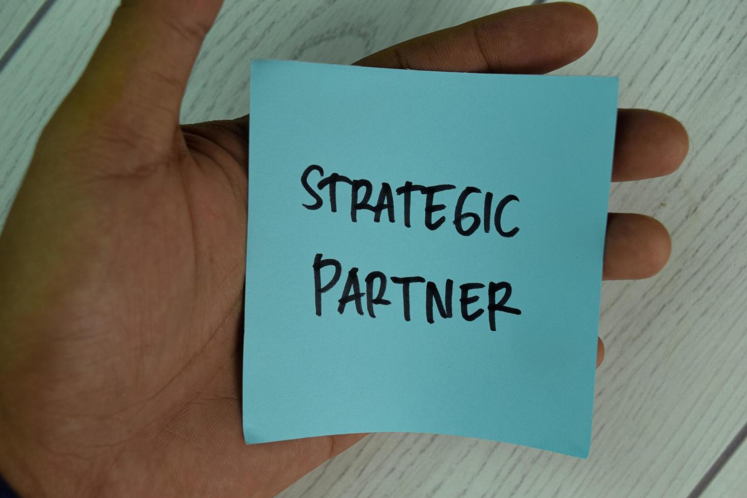 Strategic Partner written on sticky note isolated on wooden table photo