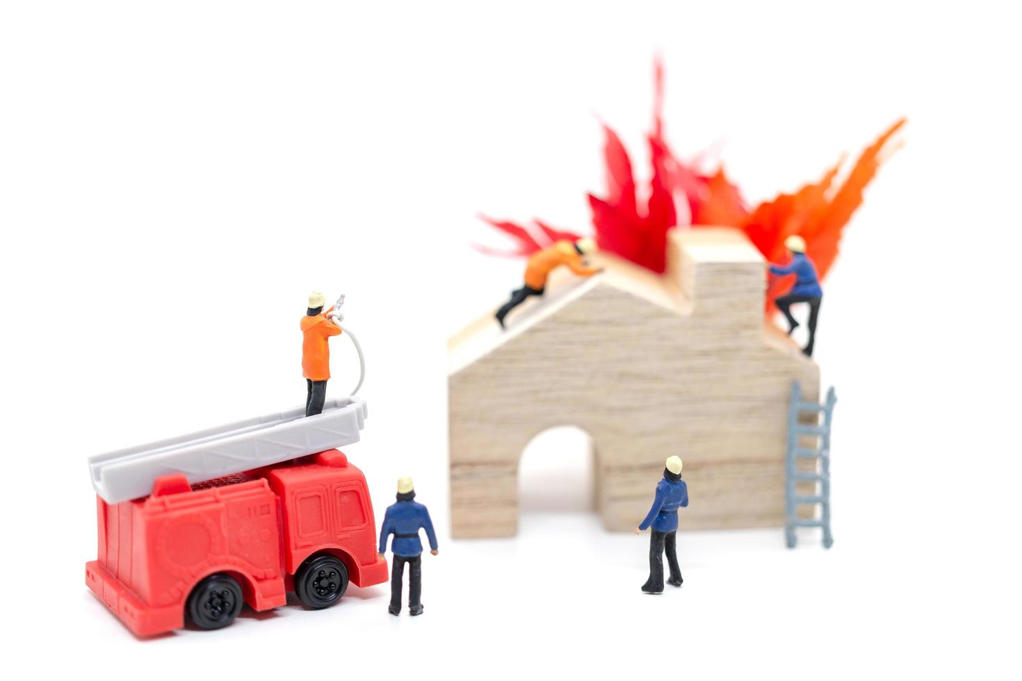 Miniature firefighters taking care of a fire emergency at a wooden house photo