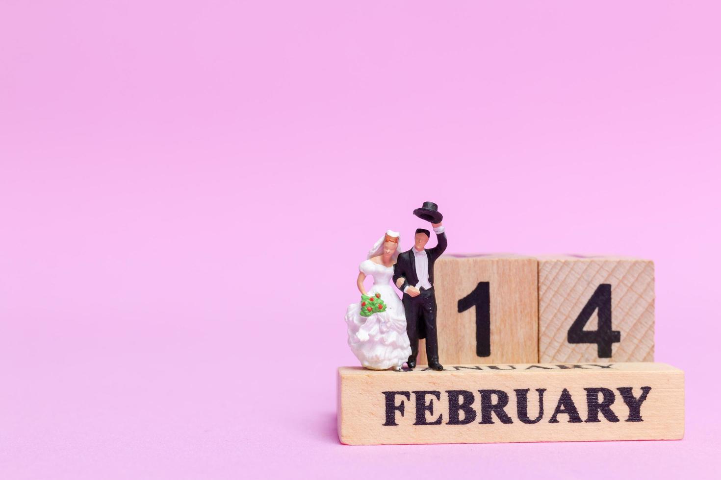 Miniature bride and groom on a pink background, Valentine's Day and wedding concept photo
