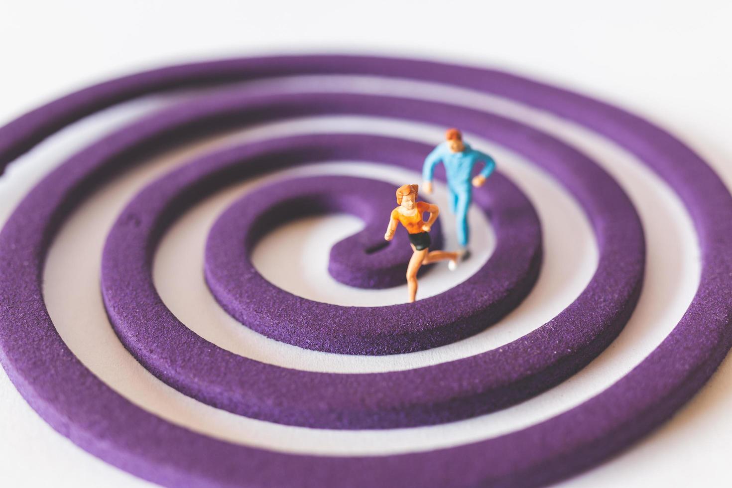 Miniature couple running on a purple circular field photo