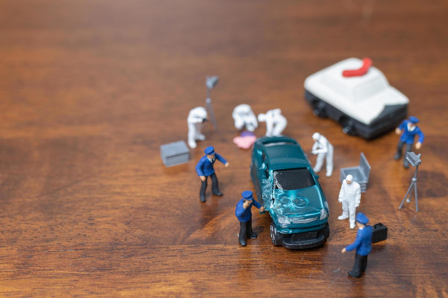 Policía en miniatura y detective de pie alrededor de un automóvil, concepto de investigación de la escena del crimen foto