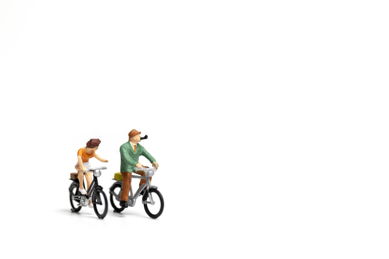 Miniature couple riding bicycles on a white background, Valentine's Day concept photo