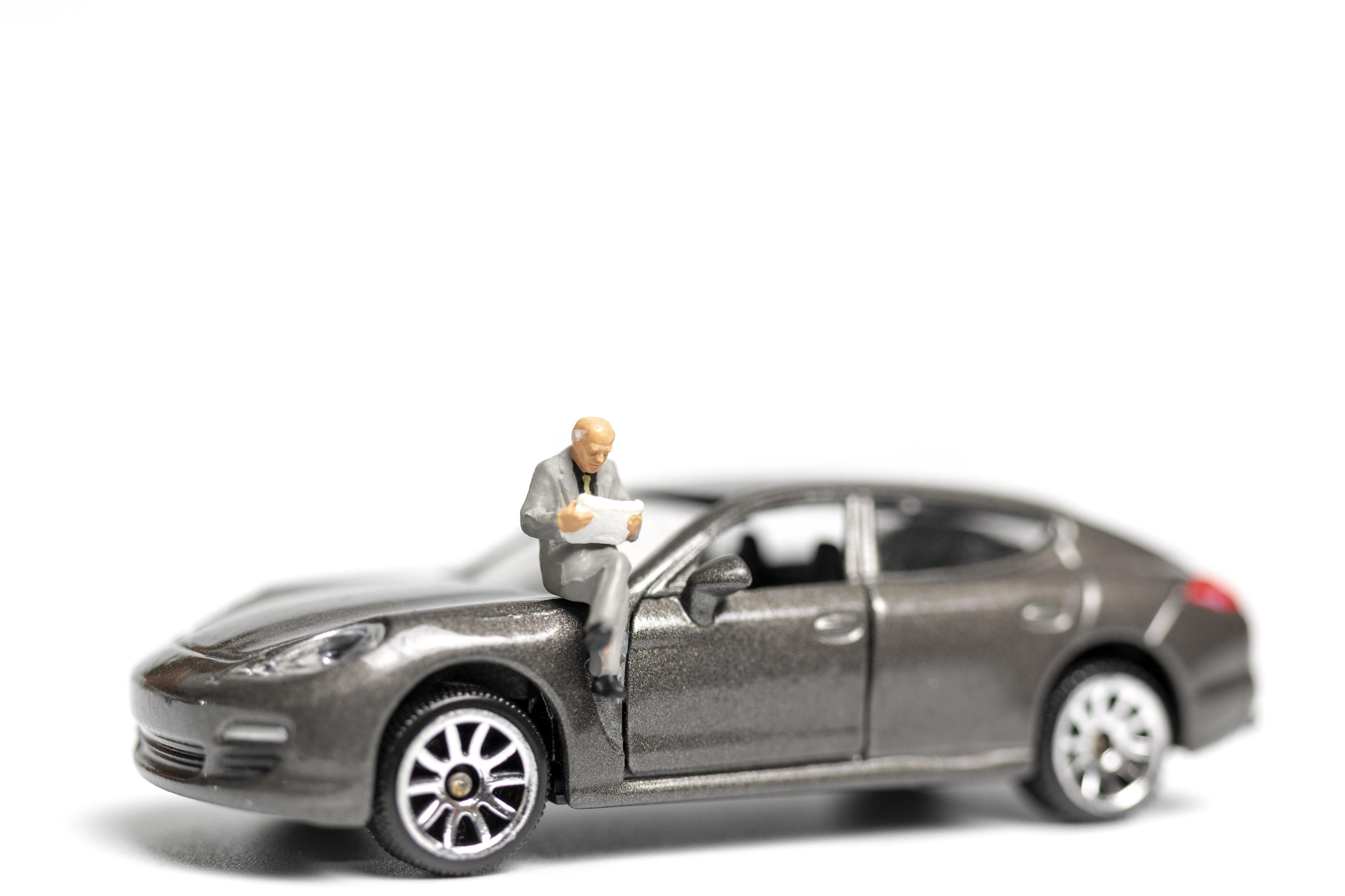 Miniature people sitting on a car on a white background 2131603 Stock Photo  at Vecteezy