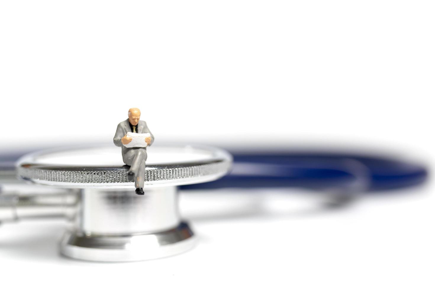 Miniature people sitting on a stethoscope on a white background, health care concept photo