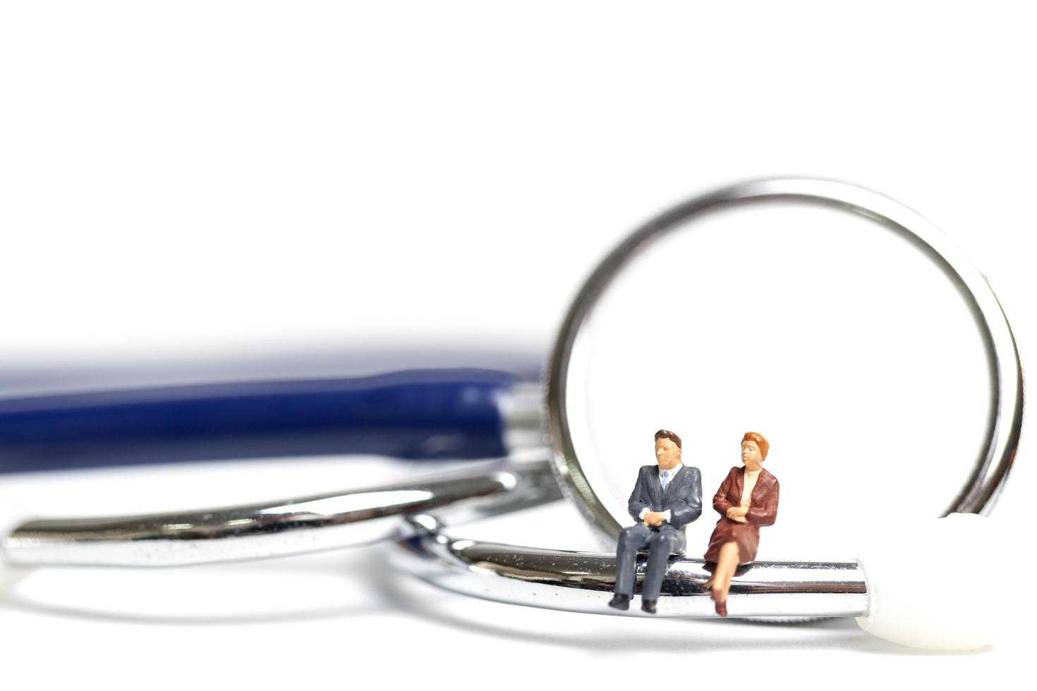 Miniature people sitting on a stethoscope on a white background, health care concept photo