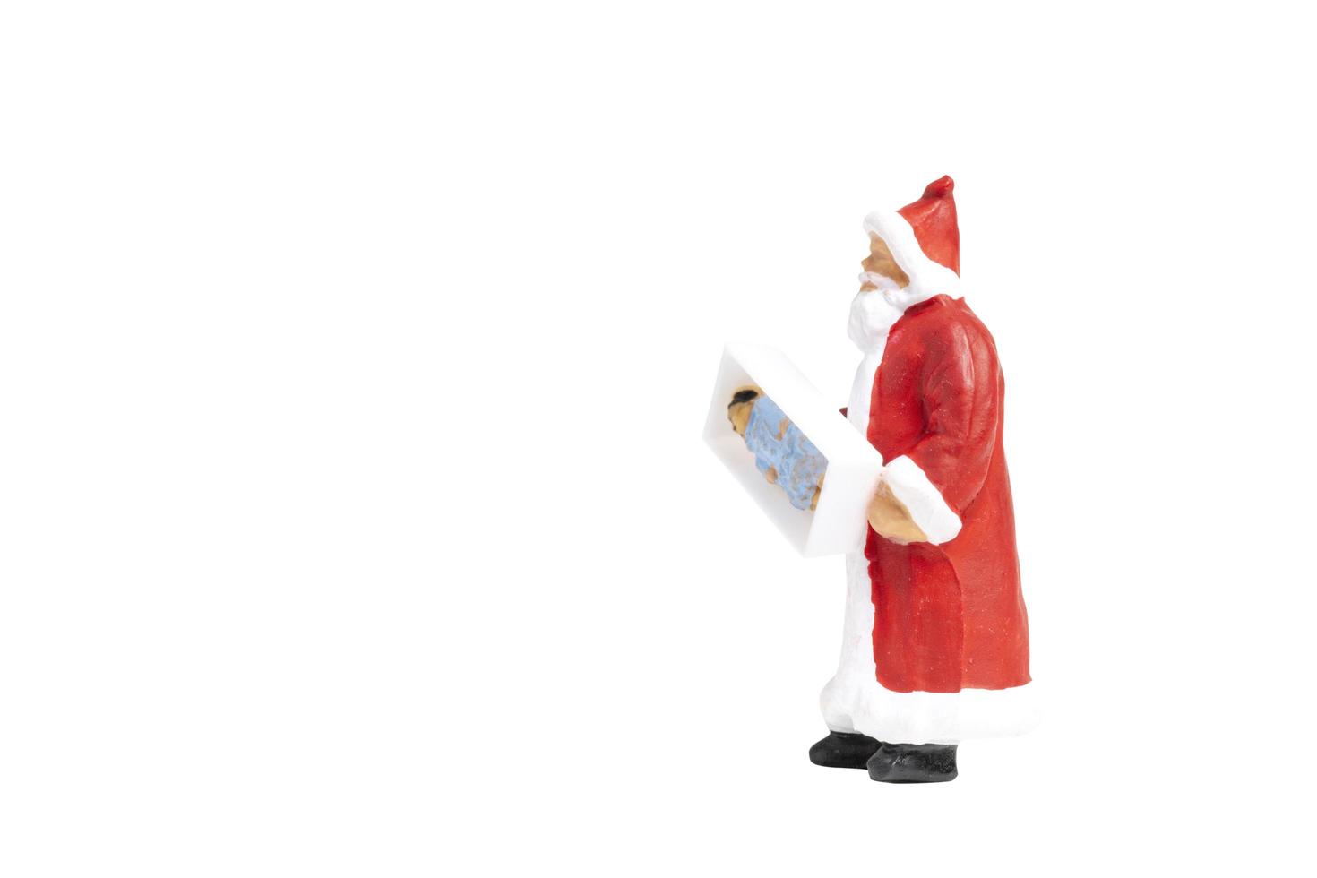 Santa Claus en miniatura sosteniendo una caja de regalo aislado sobre un fondo blanco. foto