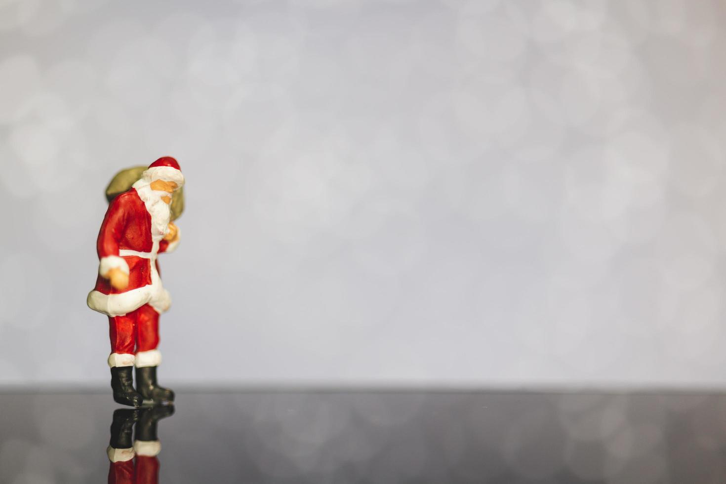 santa claus en miniatura con una bolsa sobre un fondo bokeh, feliz navidad y feliz año nuevo concepto. foto