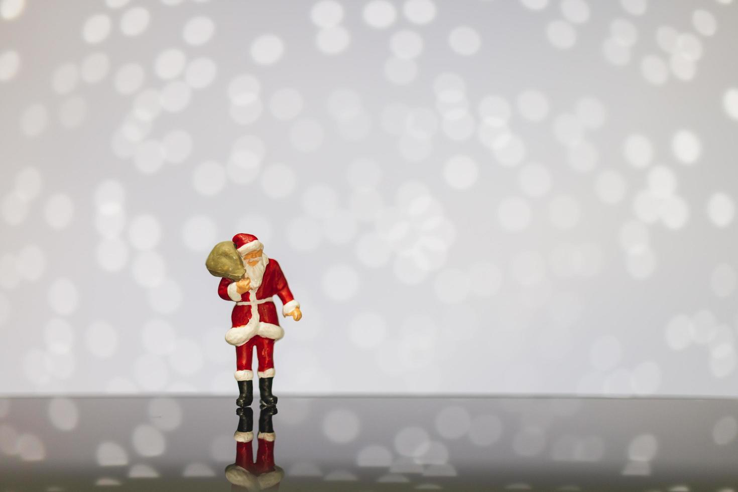 santa claus en miniatura con una bolsa sobre un fondo bokeh, feliz navidad y feliz año nuevo concepto. foto