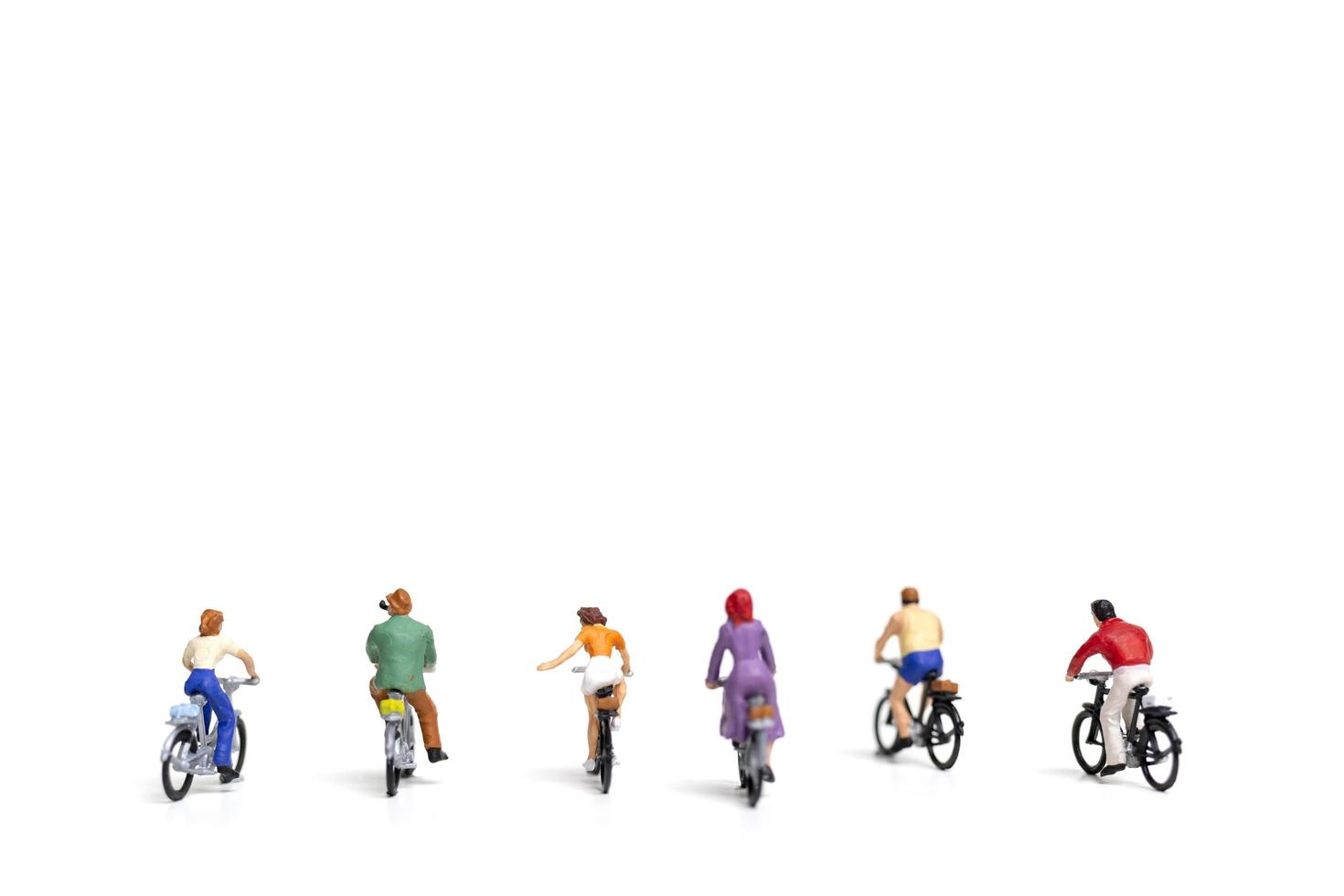 Miniature friends riding bicycles isolated on a white background, travel concept photo
