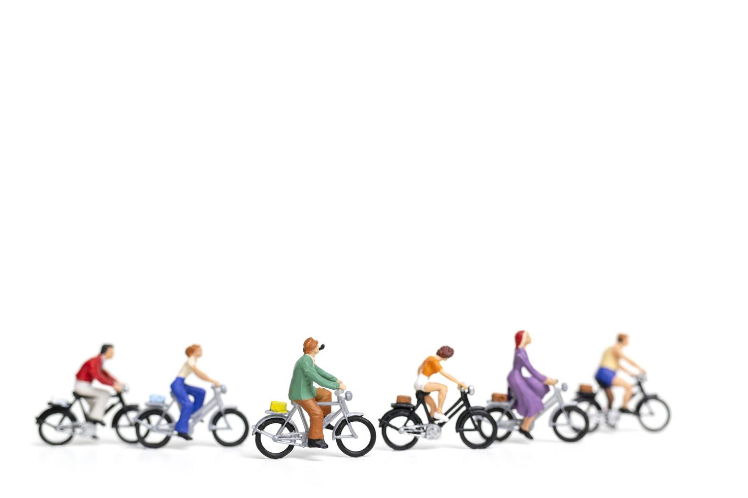 Miniature friends riding bicycles isolated on a white background, travel concept photo