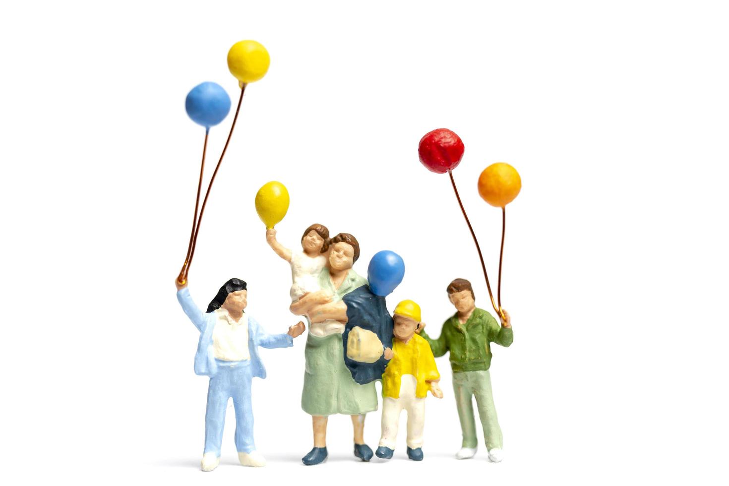 Miniature children holding balloons with a parent isolated on a white background photo