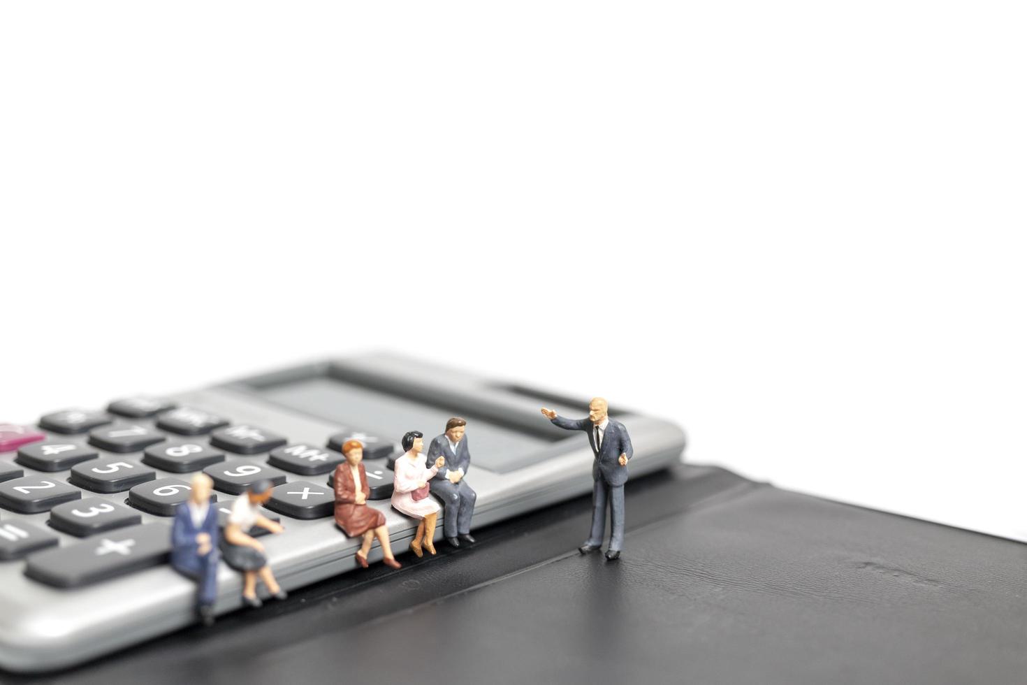 Miniature businessmen meeting on a calculator isolated on a white background, business and finance concept photo