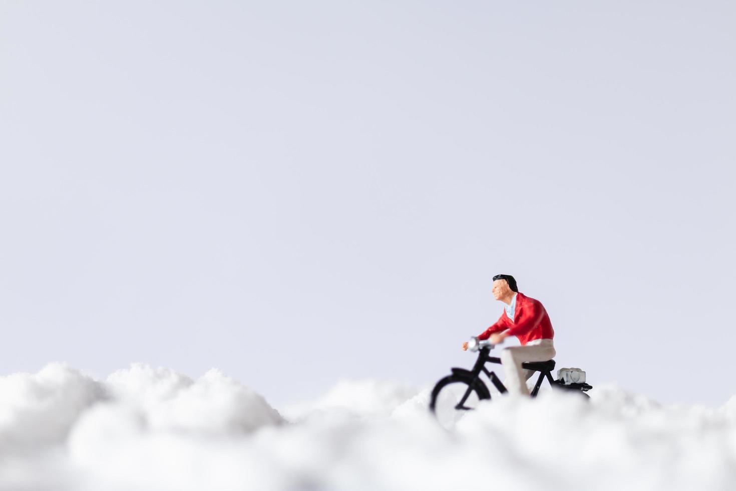 Viajeros en miniatura en bicicleta en la nieve, concepto de fondo de invierno foto