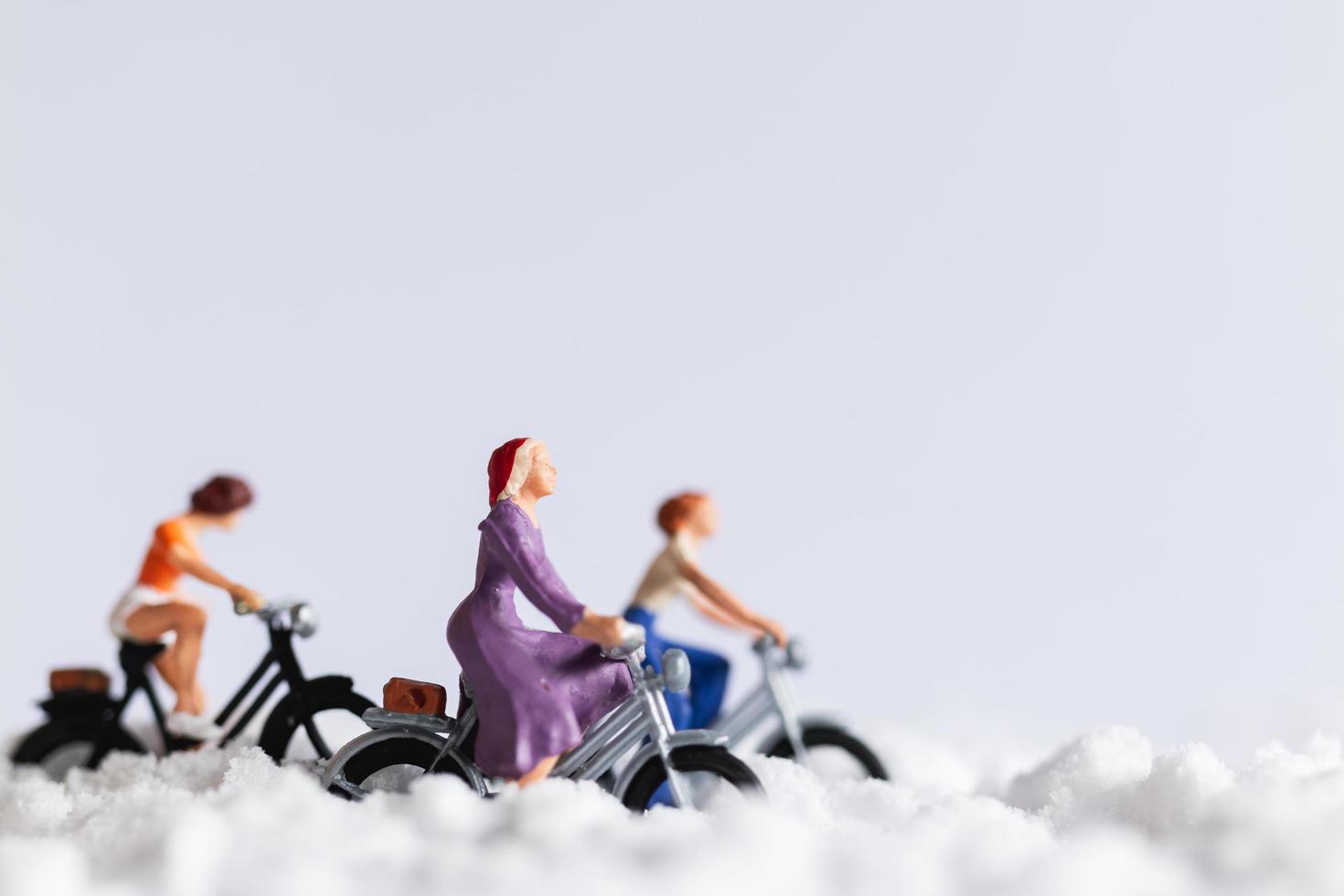 Viajeros en miniatura en bicicleta en la nieve, concepto de fondo de invierno foto