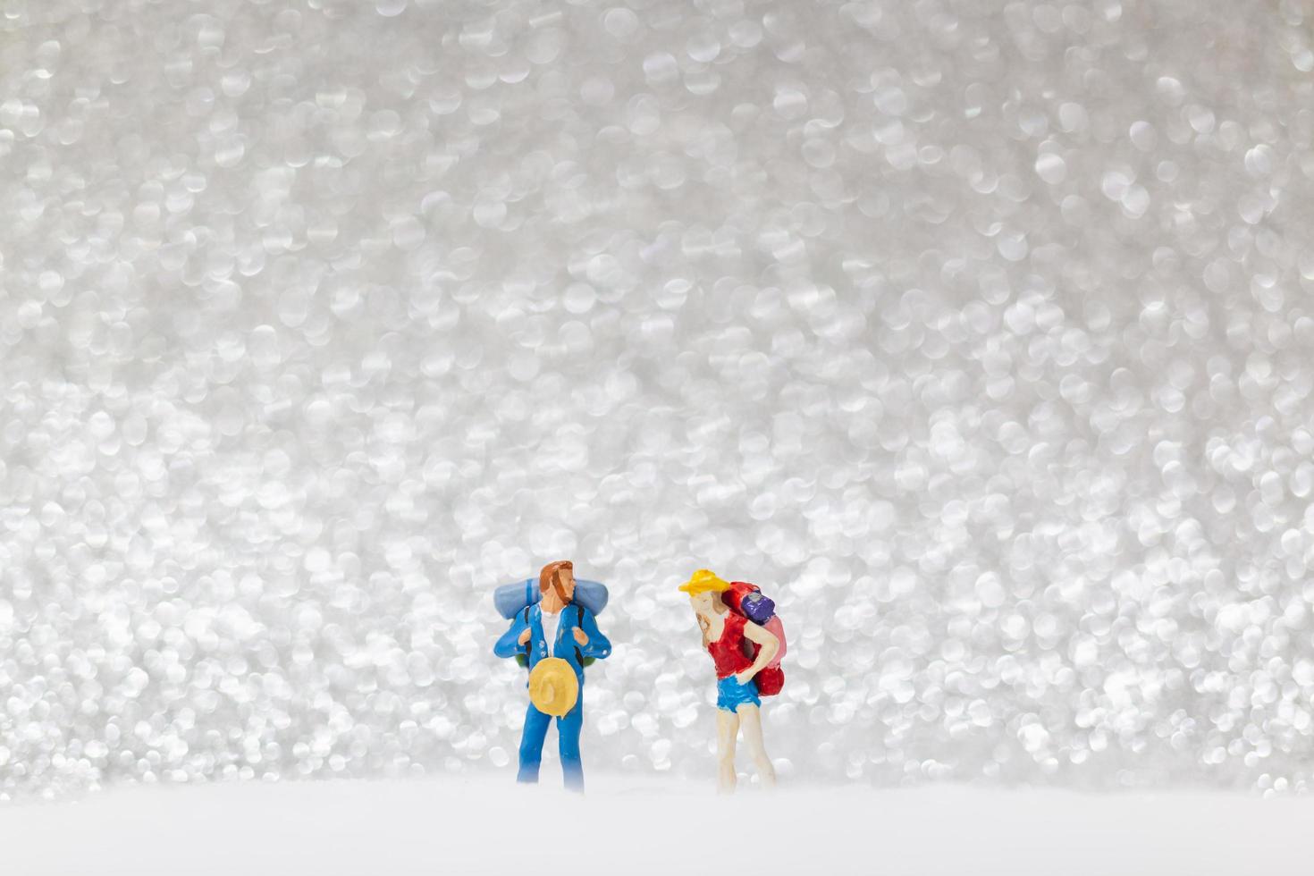 Mochileros en miniatura caminando sobre un fondo de nieve, concepto de invierno foto