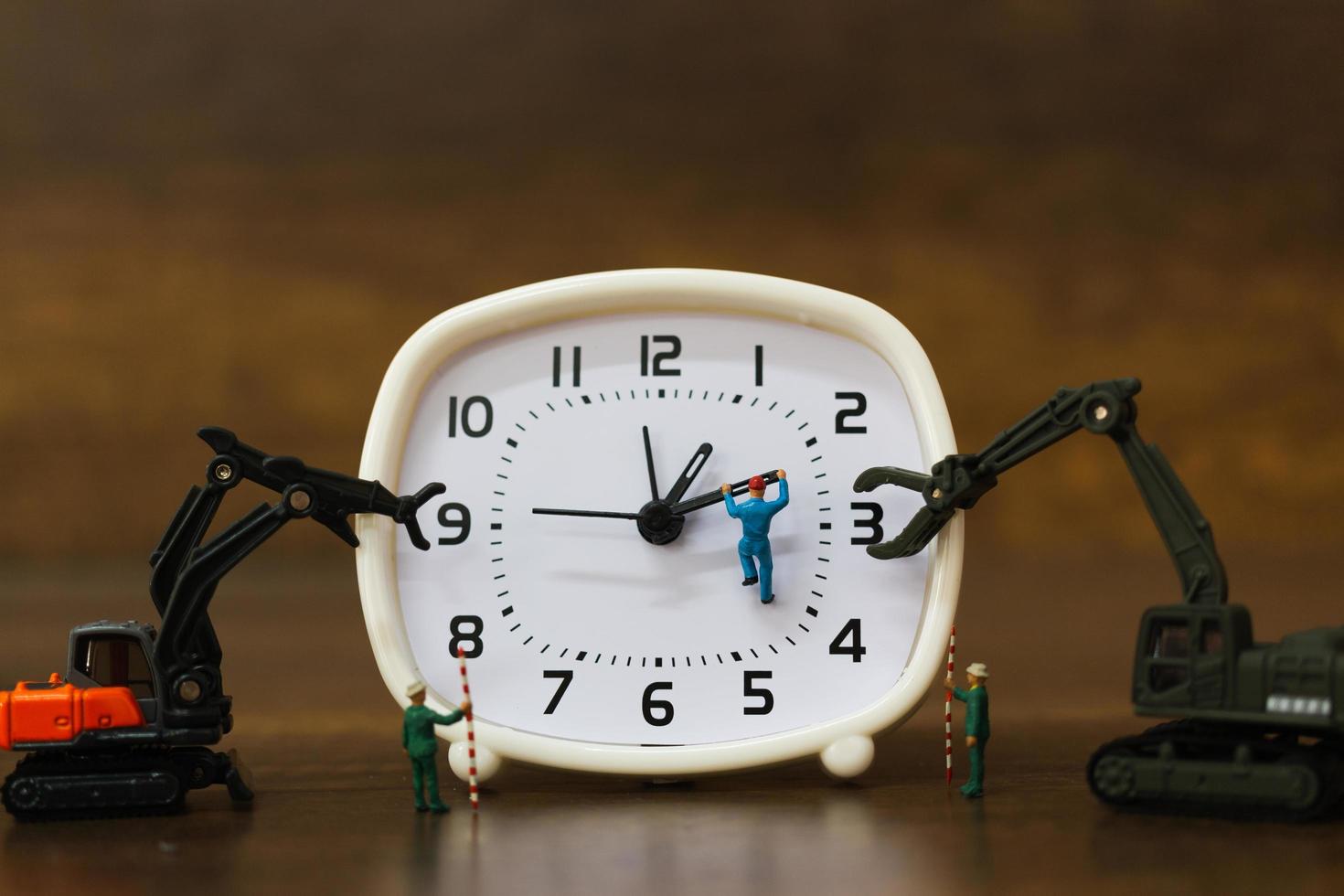 Equipo en miniatura trabajando en un reloj despertador, concepto de tiempo de trabajo foto