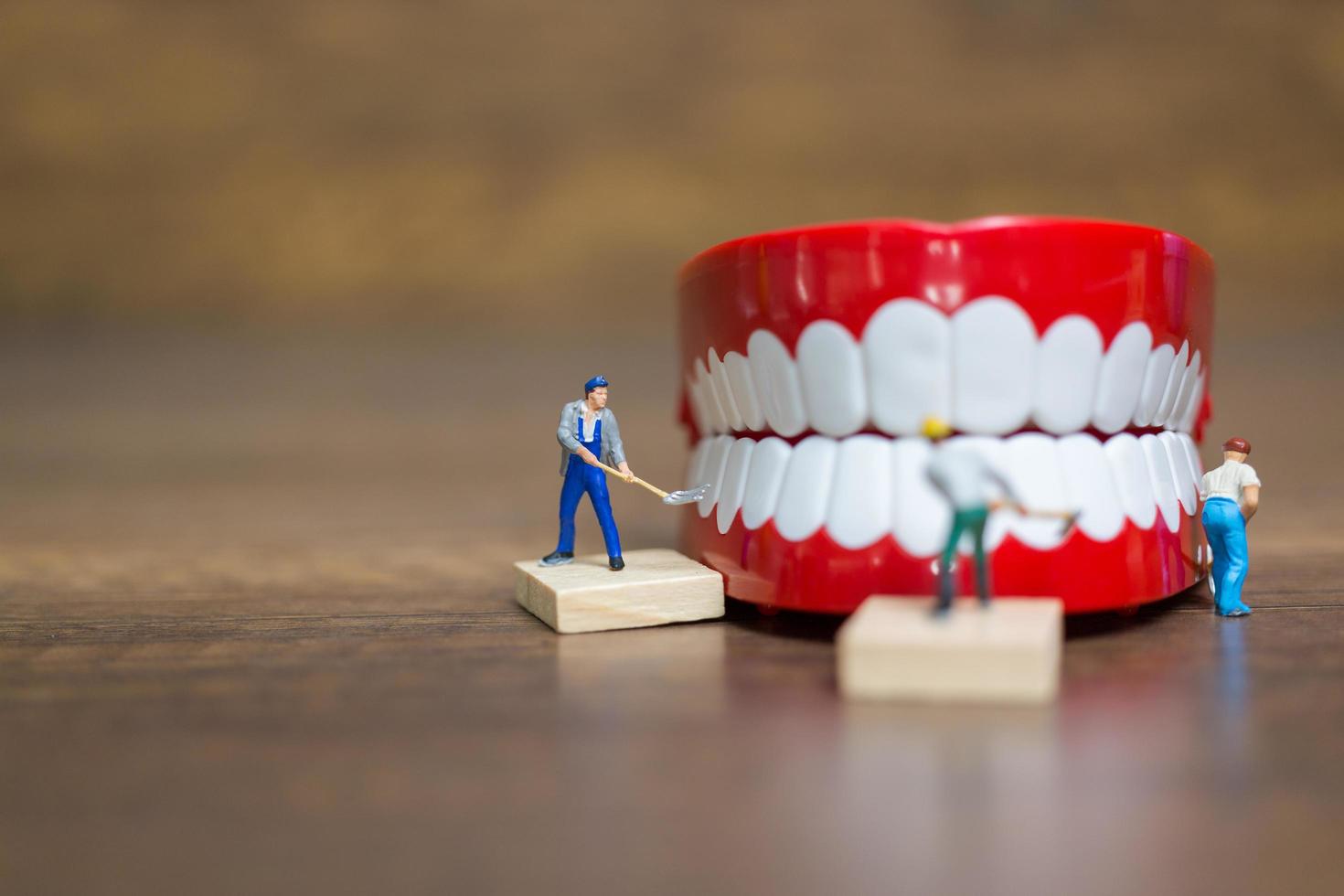 Trabajadores en miniatura reparando un diente, concepto médico y sanitario foto