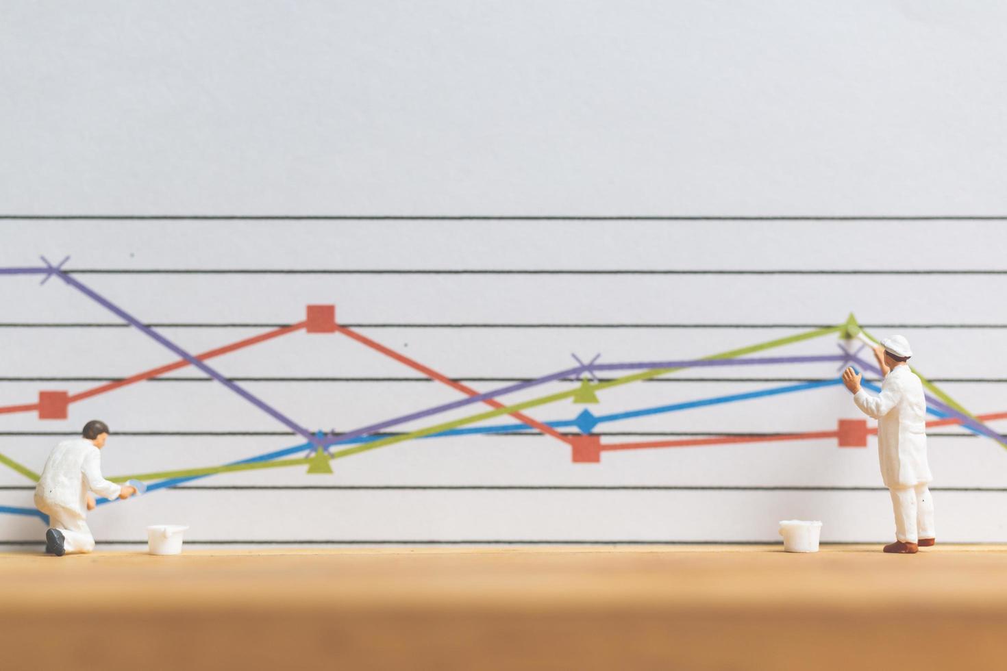 Miniature worker painting business graphs on a white background, business growth concept photo