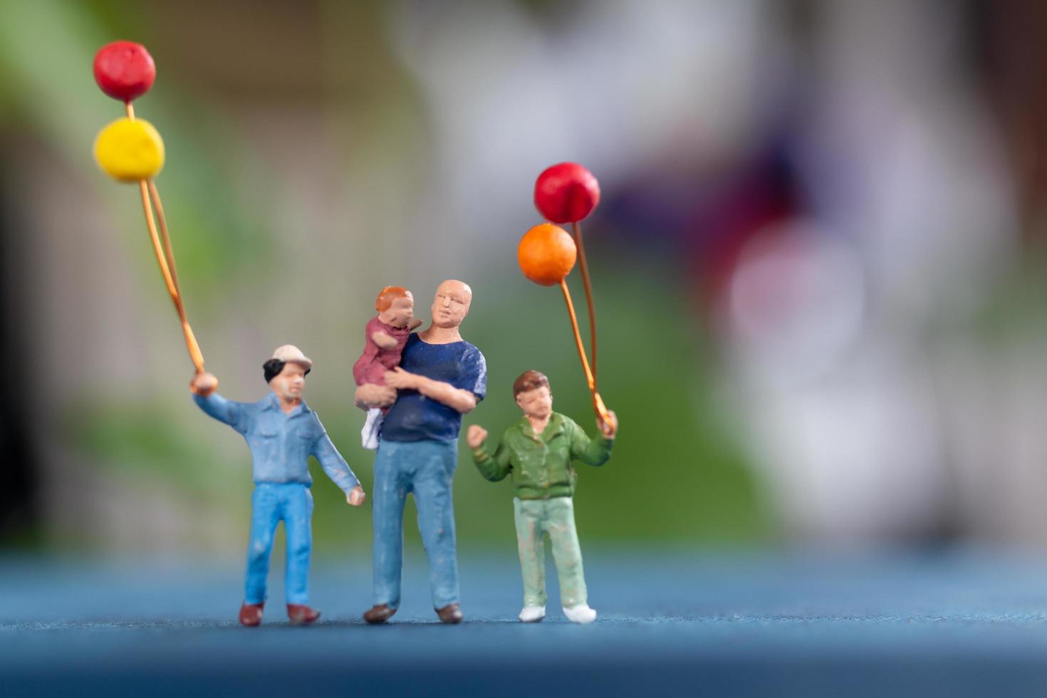 Familia en miniatura sosteniendo globos en el parque, concepto del día mundial del niño foto