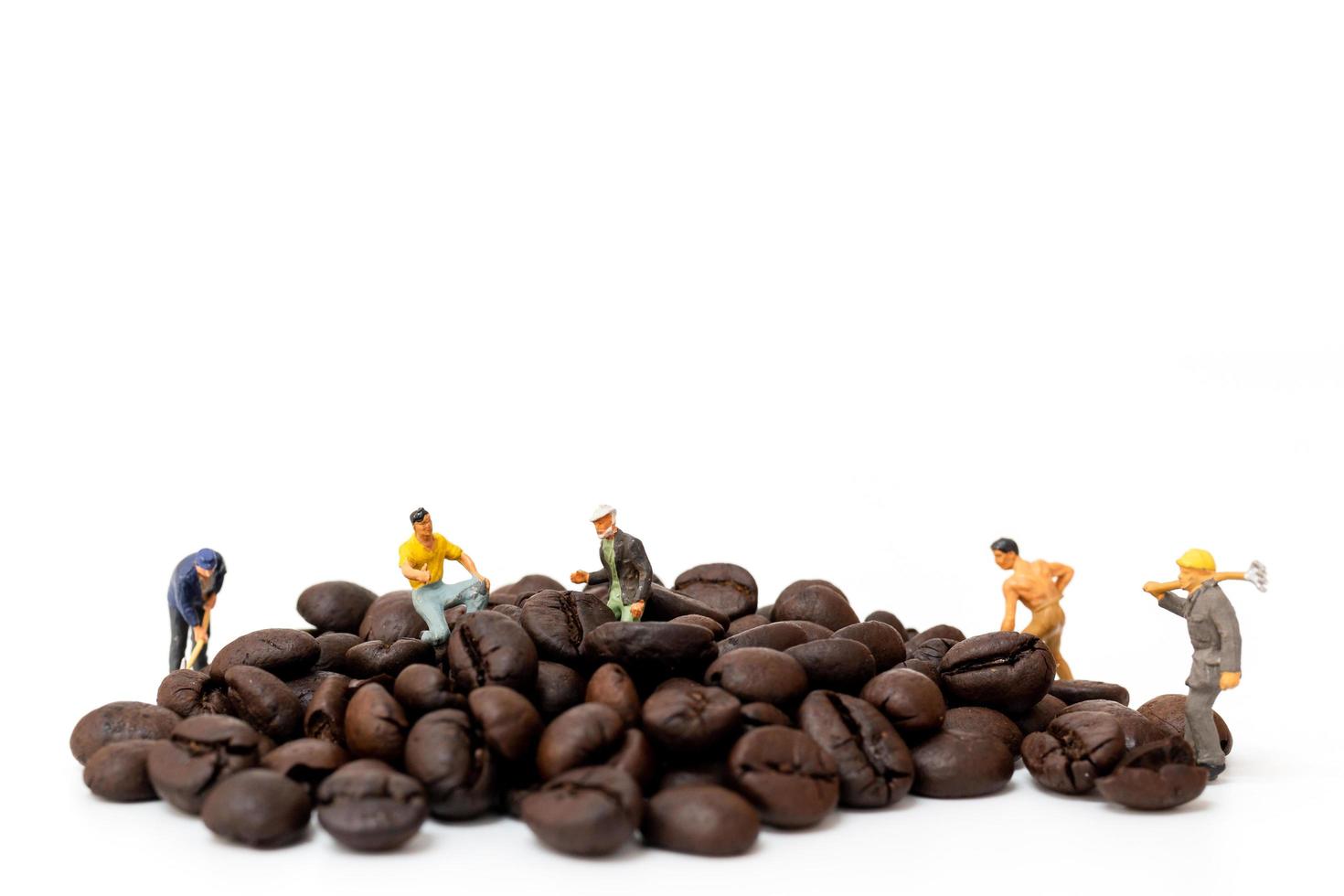 Miniature people working with roasted coffee beans on a white background, coffee time concept photo