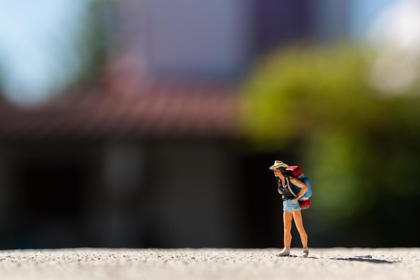 Miniature traveler with a backpack standing on a road, travel concept photo